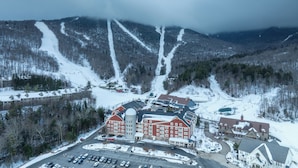 A large, red-brick hotel with multiple wings and a central tower, surrounded by snowy mountain terrain and a parking lot. - Charming 2BR/2BA Bridge-Level Condo at The Bridges Resort (Warren)