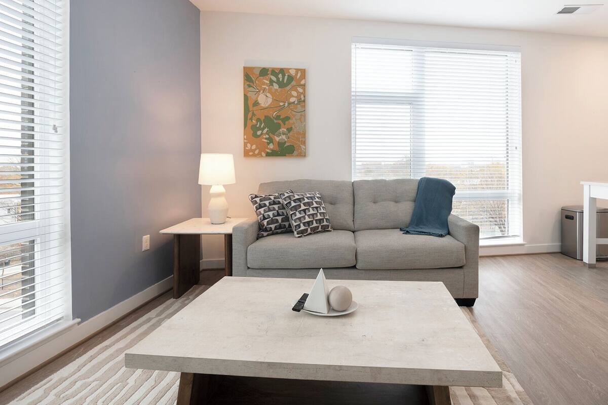 Un salon moderne avec un canapé gris, une table basse et un tableau accroché au mur.