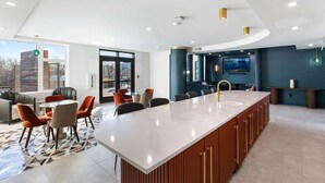 Une cuisine moderne dotée d’un grand îlot central, d’un coin repas avec des chaises et offrant une vue sur l’extérieur.