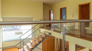 Een modern interieur met een trap, glazen balustrade en uitzicht naar buiten.