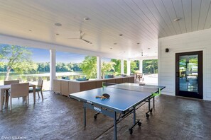 A spacious outdoor area with a ping pong table, seating, and a view of a lake. - Landing Apartments West Windsor (Windsor)