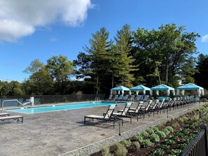Ein Pool mit Liegestühlen und Sonnenschirmen, umgeben von Bäumen.