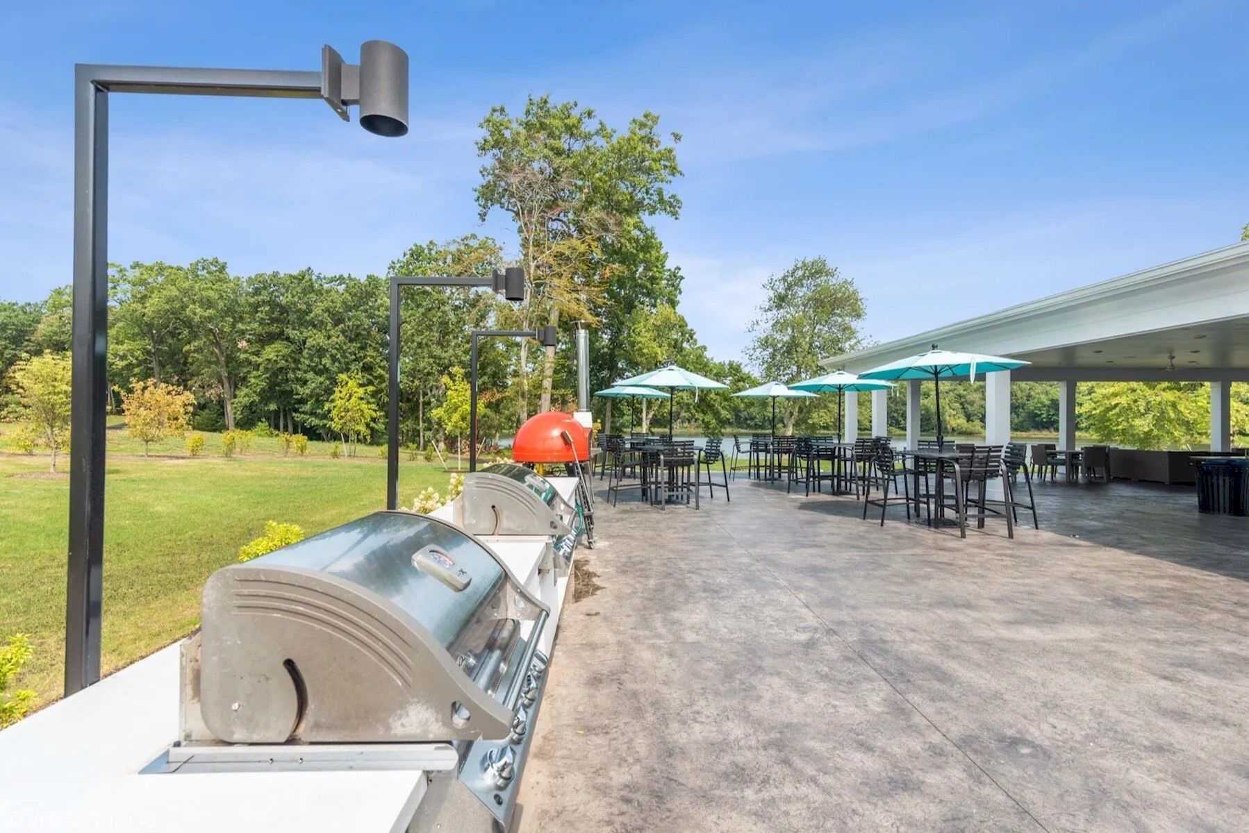 Une terrasse extérieure équipée de barbecues, de parasols et de tables.