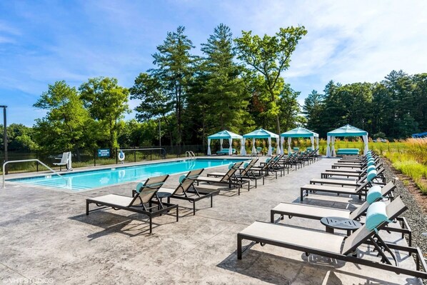 A swimming pool area with lounge chairs and gazebos. - Landing Apartments West Windsor (Windsor)