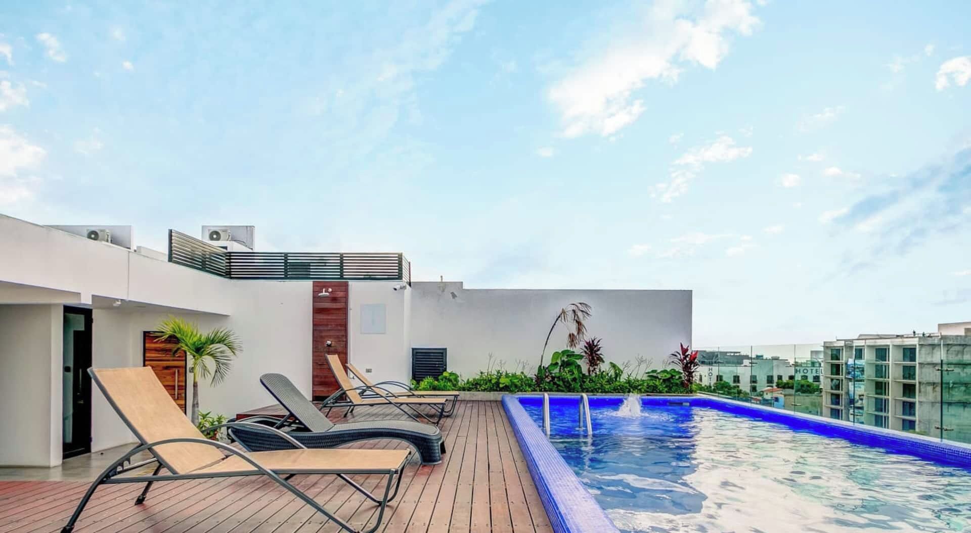 Un espace piscine aménagé sur le toit, avec des chaises longues et une piscine.