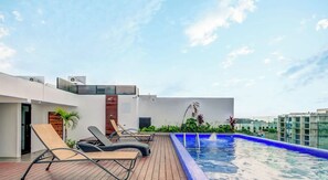 A rooftop pool area with lounge chairs and a swimming pool. - 2BR retreat w/ rooftop pool & BBQ (Playa del Carmen)