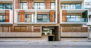 A modern multi-story building with a central entrance, large windows, and a balcony on the upper floor. - Vibrant Condo by 5th Ave | Roof Pool | Gym | BBQ (Playa del Carmen)