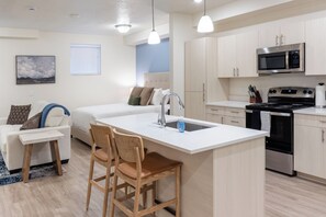 A modern kitchen with a central island, stainless steel appliances, and light wood cabinetry. - Landing Apartments Salt Lake City (Salt Lake City)