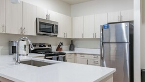 Una cucina moderna con elettrodomestici in acciaio inossidabile, un forno a microonde integrato e un frigorifero.