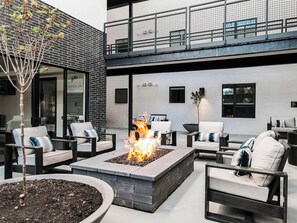 An outdoor seating area with a fire pit, lounge chairs, and a modern building with a balcony. - Landing Apartments Salt Lake City (Salt Lake City)