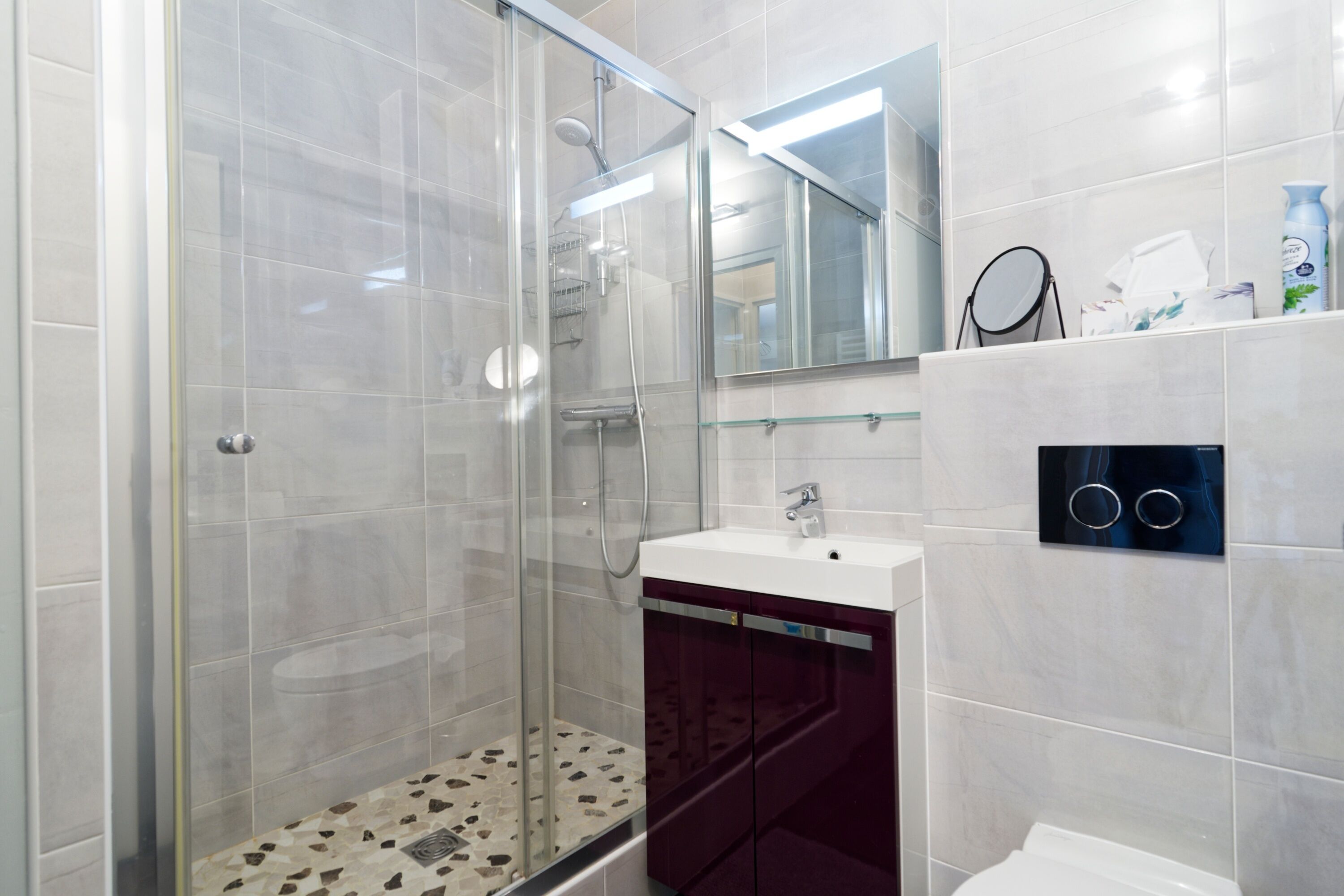 A modern bathroom with a glass-enclosed shower, a vanity with a mirror, and a toilet.