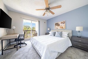 Ein Schlafzimmer mit Bett, Schreibtisch, Stuhl und Deckenventilator.