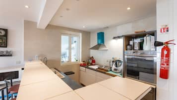 A modern kitchen with a large island, stainless steel appliances, and a fire extinguisher.