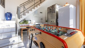 Una cucina moderna con un tavolo da calcio, un frigorifero in acciaio inox e una scala che conduce a un piano superiore.