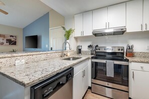 A modern kitchen with white cabinets, a granite countertop, stainless steel appliances, and a potted plant. - Landing | Beautiful 1BD, Tennis Court, Gym (Palm Bay)