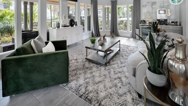 Ein modernes Wohnzimmer mit einem grünen Sofa, einem Couchtisch und einem an der Wand befestigten Fernseher.