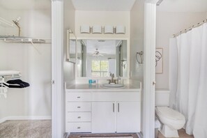 A bathroom with a white vanity, a large mirror, a ceiling fan, and a toilet. - Landing | Spectacular 1BD, Gym, Tennis Court (Palm Bay)