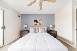 A bedroom with a bed, two nightstands, a ceiling fan, and a wall art piece. - Landing | Spectacular 1BD, Gym, Tennis Court (Palm Bay)