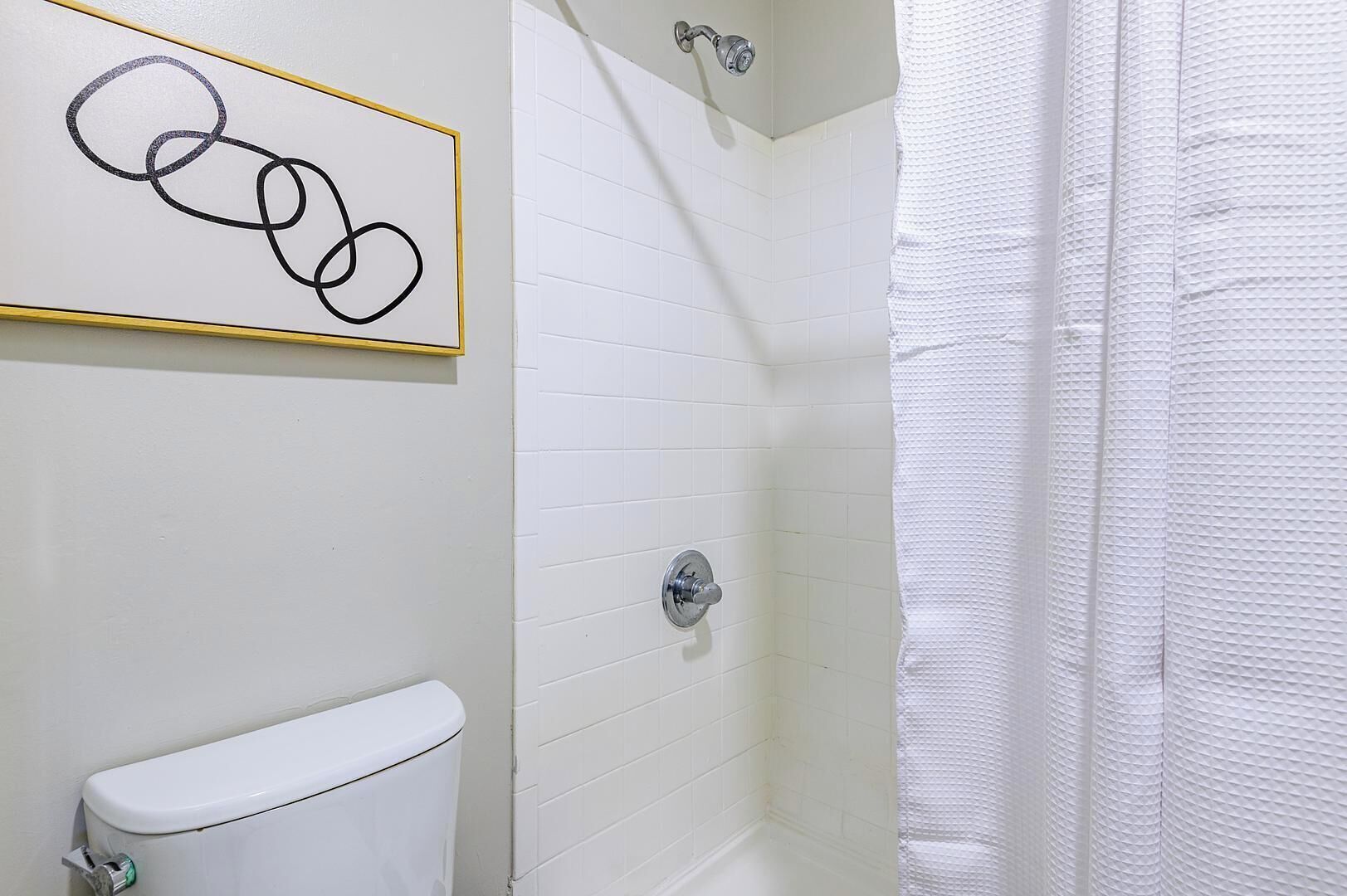 A bathroom with a toilet, a shower with a glass door, and a wall-mounted sink.