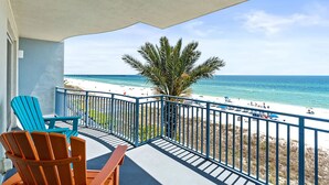 A balcony with two chairs, a view of the beach, and a palm tree. - Sterling Breeze 307 (Panama City Beach)