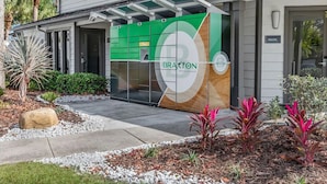 A modern building with a green and white facade, labeled "BRAXTON PREMIER APARTMENTS". - Landing | Incredible 2BD, Gym, Tennis Court (Palm Bay)