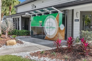 A modern building with a green and white facade, labeled "BRAXTON PREMIER APARTMENTS". - Landing | Incredible 2BD, Gym, Tennis Court (Palm Bay)