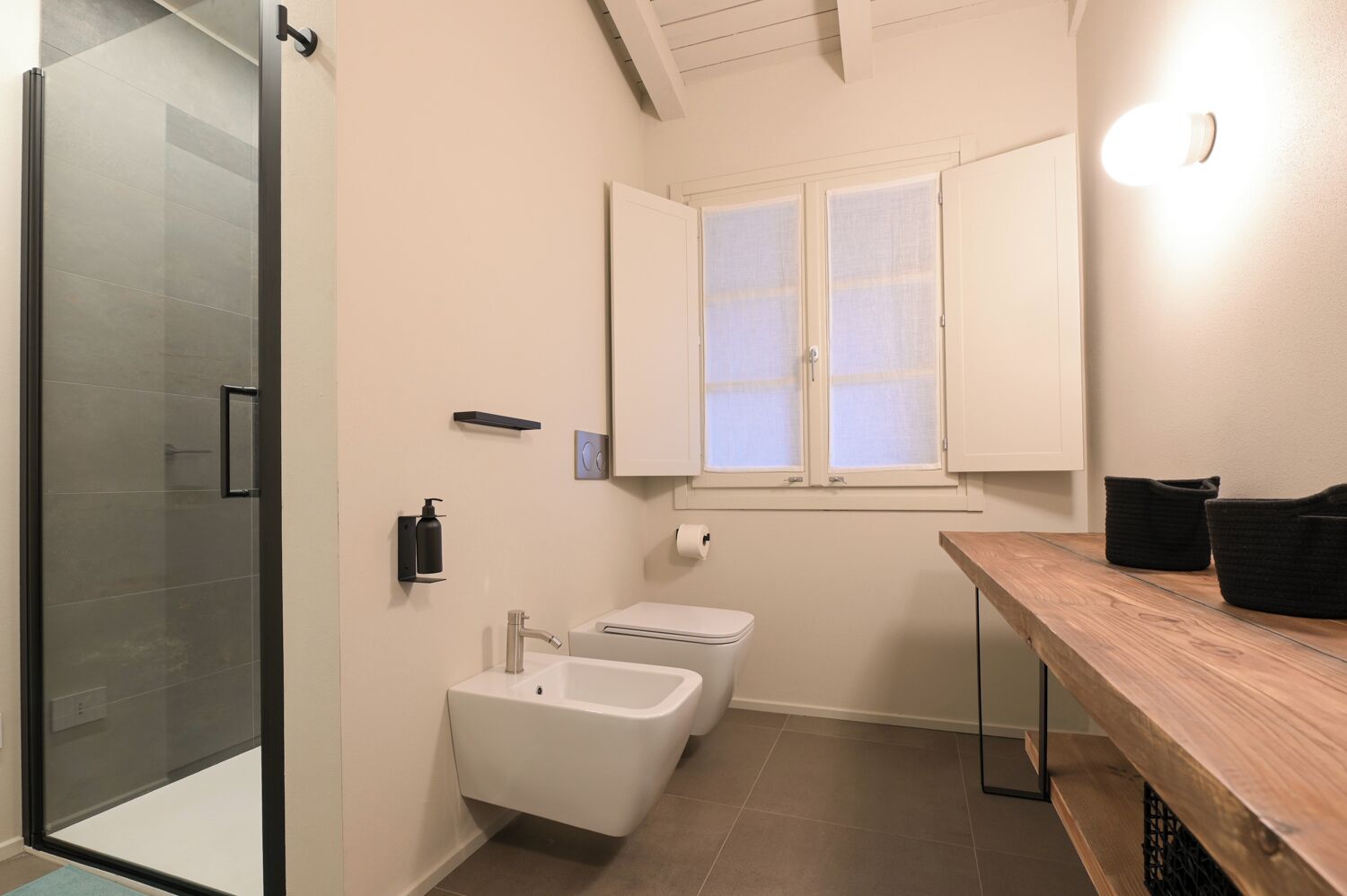 Ein modernes Badezimmer mit Duschkabine aus Glas, Waschbecken, Toilette und einem Holz-Waschtisch.