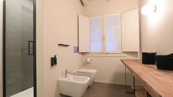 Une salle de bain moderne avec une douche à l’italienne en verre, un lavabo, des toilettes et un meuble-lavabo en bois.