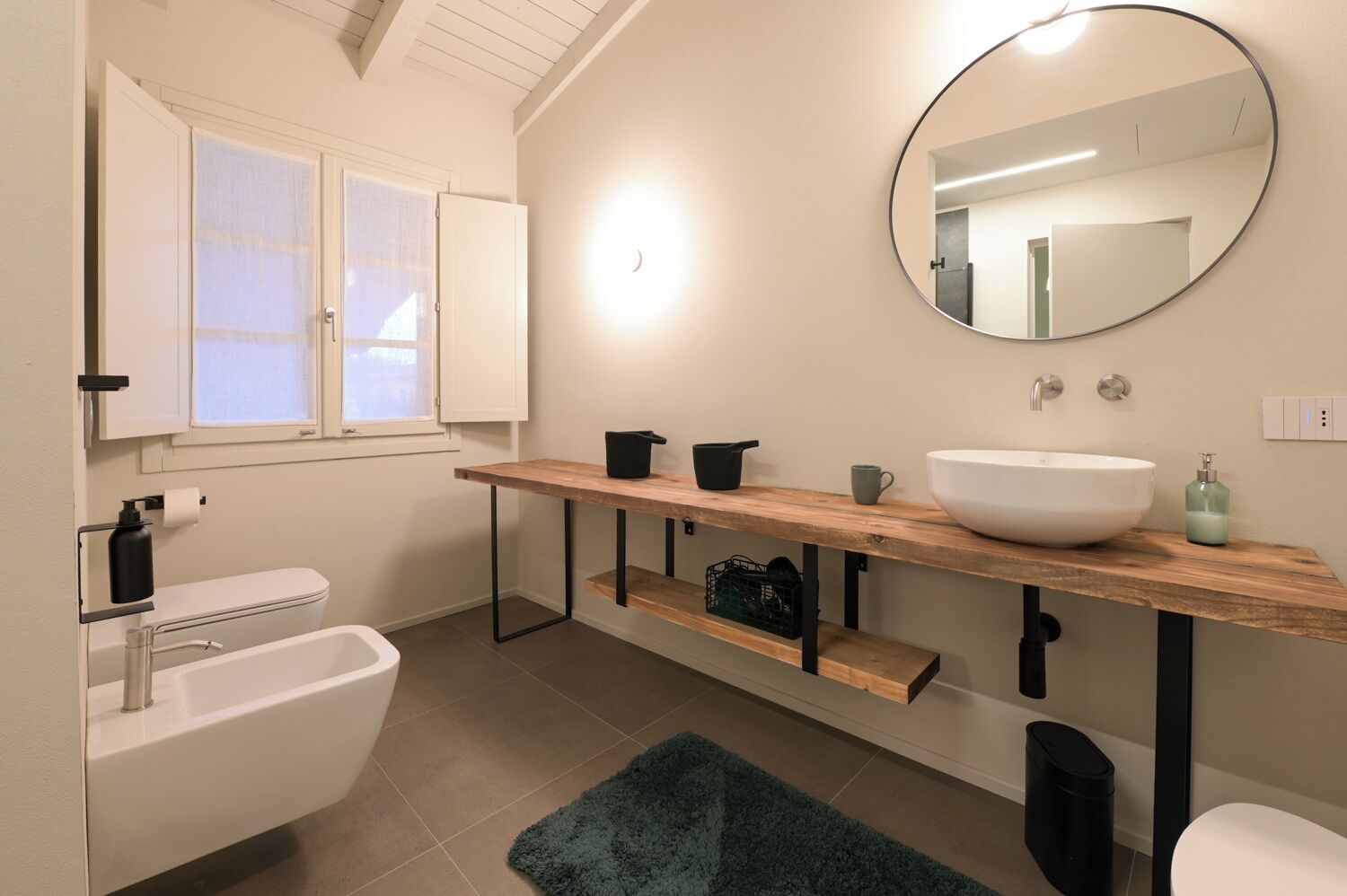 Ein Badezimmer mit einer weißen Badewanne, einem weißen Waschbecken, einer Holzausstattung, einem Spiegel und einem Fenster mit Milchglas.