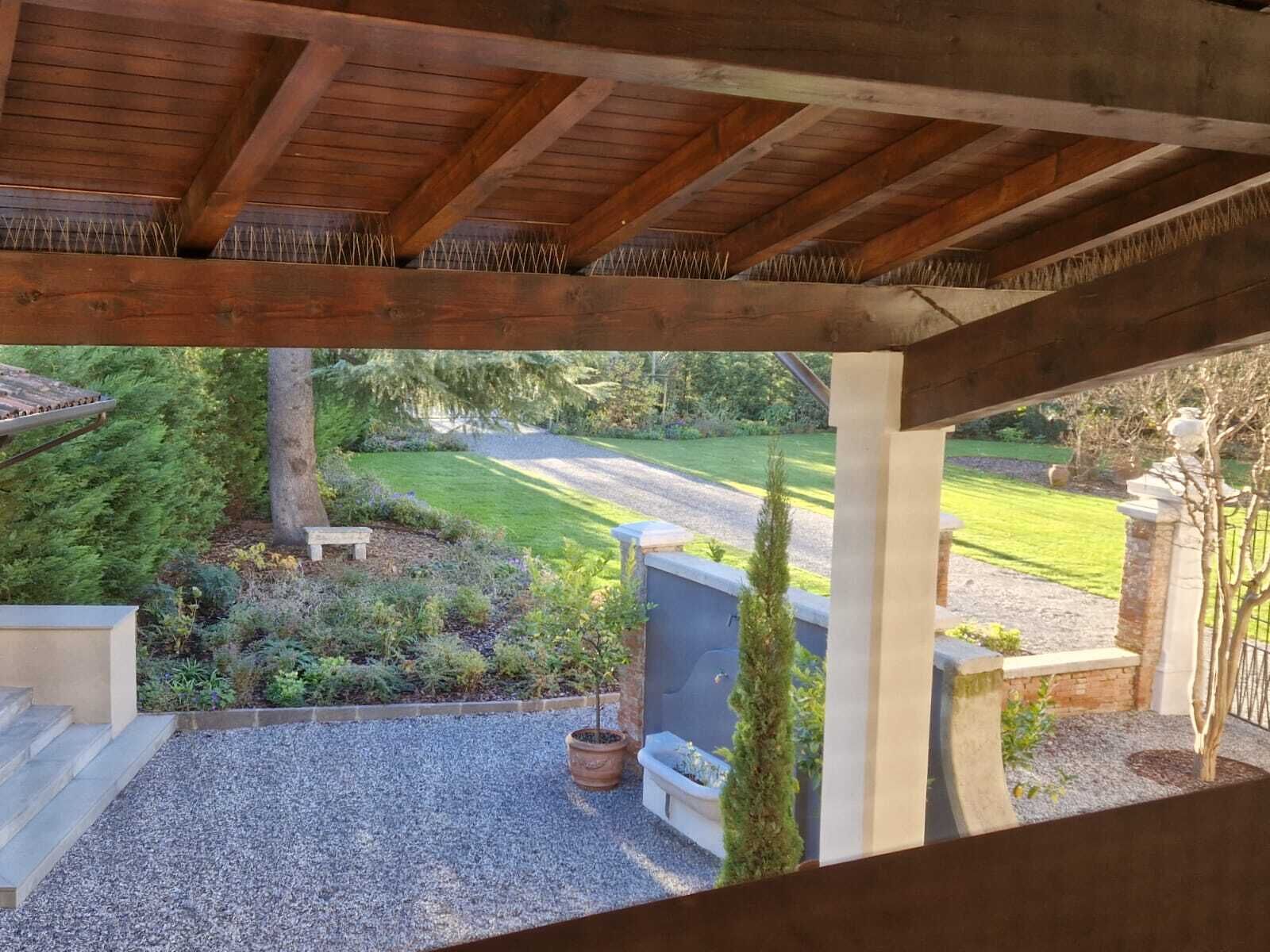 Eine überdachte Terrasse mit Blick auf einen gepflegten Garten und einen Weg zu einem Haus.