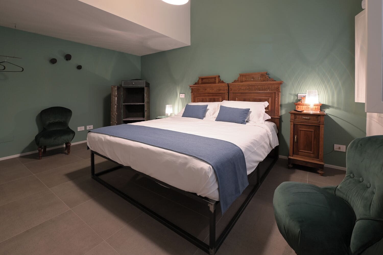Un dormitorio con cama, una silla, un armario y una lámpara.