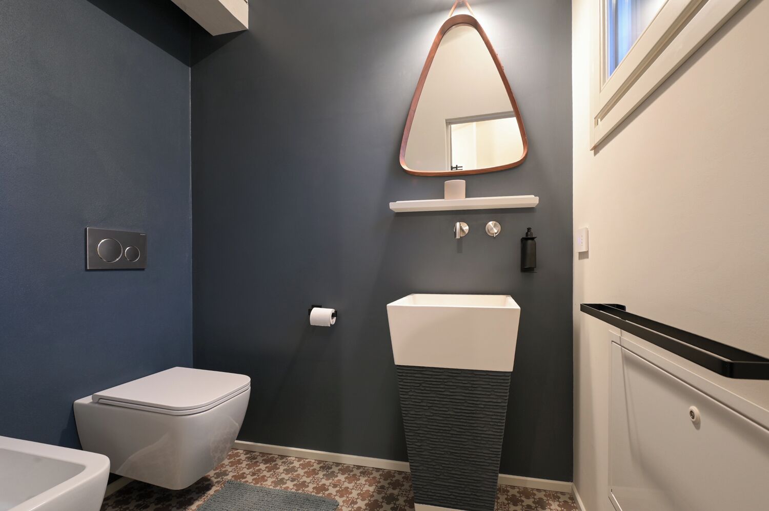 Un baño moderno con inodoro, lavamanos y espejo.