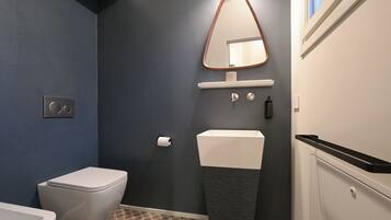 Ein modernes Badezimmer mit Toilette, Waschbecken und Spiegel.