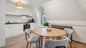 Une cuisine moderne avec des meubles blancs, une table ronde en bois et quatre chaises.