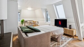 Une chambre de style loft moderne, dotée d’un grand lit, d’une télévision et d’un coin repas.