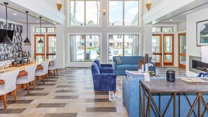 Un amplio vestíbulo de hotel con una zona de estar espaciosa, un bar y grandes ventanales que ofrecen vistas de la piscina exterior y los alrededores.