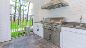 Una cocina compacta con una parrilla integrada, una campana extractora de acero inoxidable y un lavamanos.