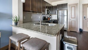 A kitchen with granite countertops, stainless steel appliances, and dark wooden cabinets. - Landing | Stunning 1BD, Clubhouse, Gym (Houston)