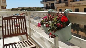 Ein Balkon mit einem Holzstuhl und Topfpflanzen.