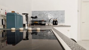 Eine Küche mit schwarzem Arbeitsplatz, einer Kaffeemaschine und einem Wasserkocher.