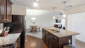 A modern kitchen with dark wood cabinets, granite countertops, and stainless steel appliances. - Landing | Beautiful 1BD, Clubhouse, Pool (Greenville)