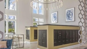 Un hall d’hôtel spacieux, doté d’un comptoir d’accueil central, d’un éclairage moderne suspendu et de grandes fenêtres laissant entrer la lumière naturelle.