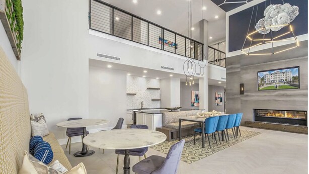 Un vaste espace de vie doté d’un haut plafond, d’une cheminée et d’un coin repas avec des chaises bleues.