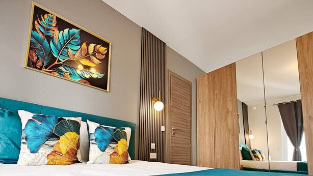 Een moderne slaapkamer met een groot bed, een wanddecoratie, een kledingkast en een spiegel.