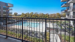 A modern building with a pool area, including lounge chairs and a sign warning against diving. - Landing | Incredible 1BD, Rooftop Lounge, Pool (Memphis)