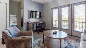 A modern living room with a sofa, a coffee table, and a TV mounted on the wall. - Landing | Incredible 1BD, Rooftop Lounge, Pool (Memphis)