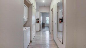 Un pasillo estrecho con área de lavandería a la izquierda, cocina en el centro y armario con espejo a la derecha.