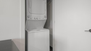 Una lavadora y secadora compacta, blanca e integrada en la pared, con un panel de control que incluye varios diales y botones.