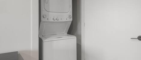 A compact, white, wall-mounted washer and dryer unit with a control panel featuring multiple dials and buttons.