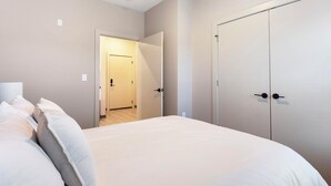 A bedroom with a bed, a wardrobe, and a door leading to another room. - Landing | Amazing 1BD, Rooftop Lounge, Yoga Studio (Memphis)